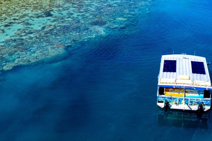 a blue and white boat sitting next to a body of water